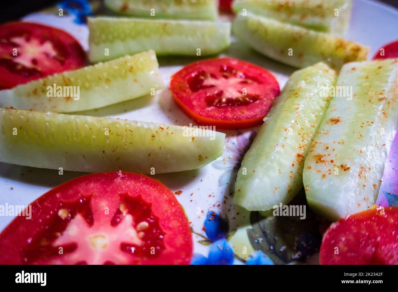 A green Salad Plate with cucumber and tomatoes, Sprinkled spices on top. Vegan Diet. India. Stock Photo