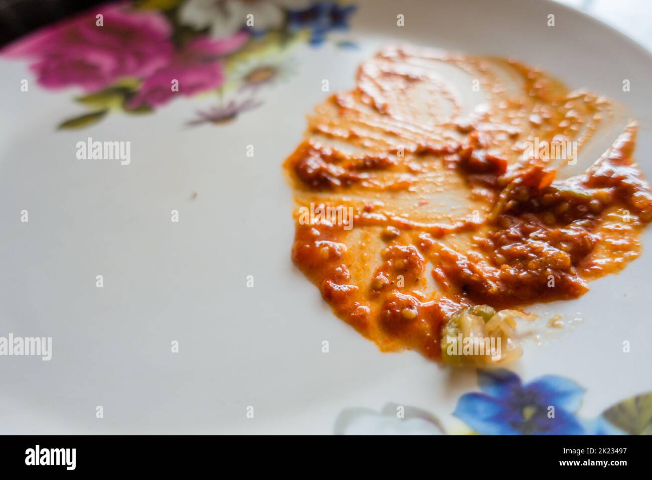 An after snack empty white plate with left over red sauce. India Stock Photo