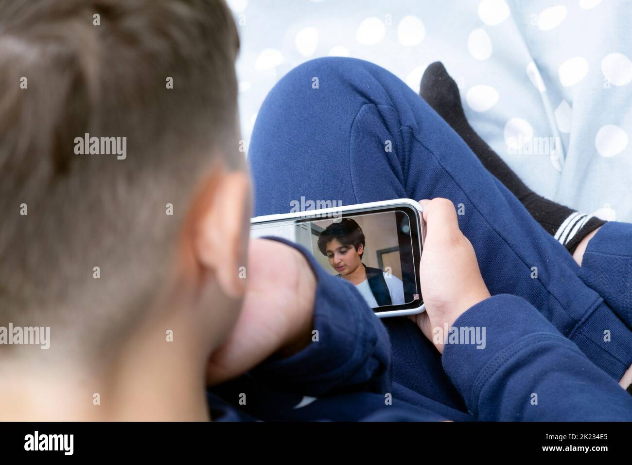 Boy child 12 back of head looking down at mobile phone viewing social media Dhar Mann Youtube video in UK 2022 Great Britain  KATHY DEWITT Stock Photo