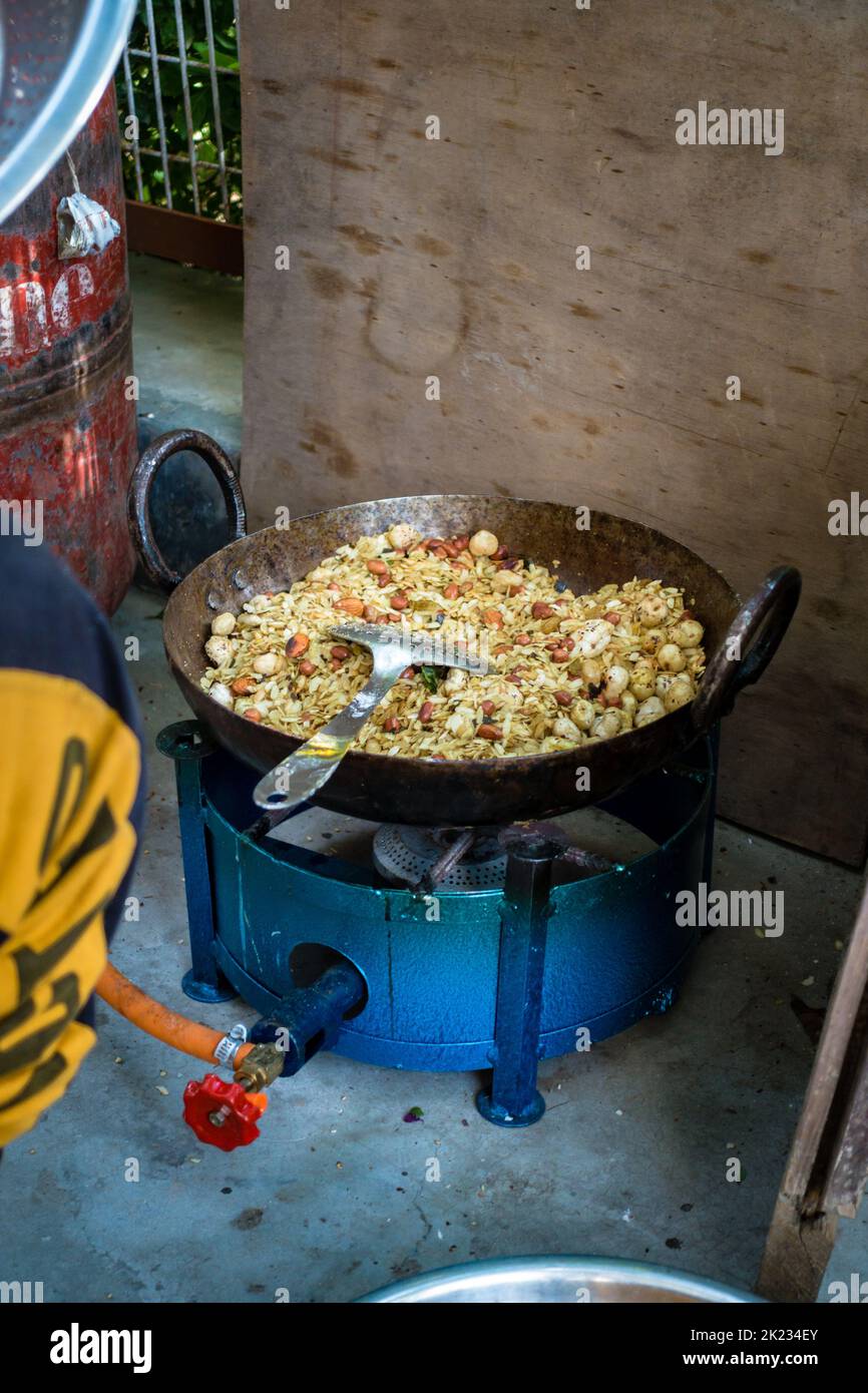 Preparing Homemade granola with oats, buckwheat, nuts and seeds in a big cast iron cauldron or kadai on a traditional stove. Uttarakhand India Stock Photo