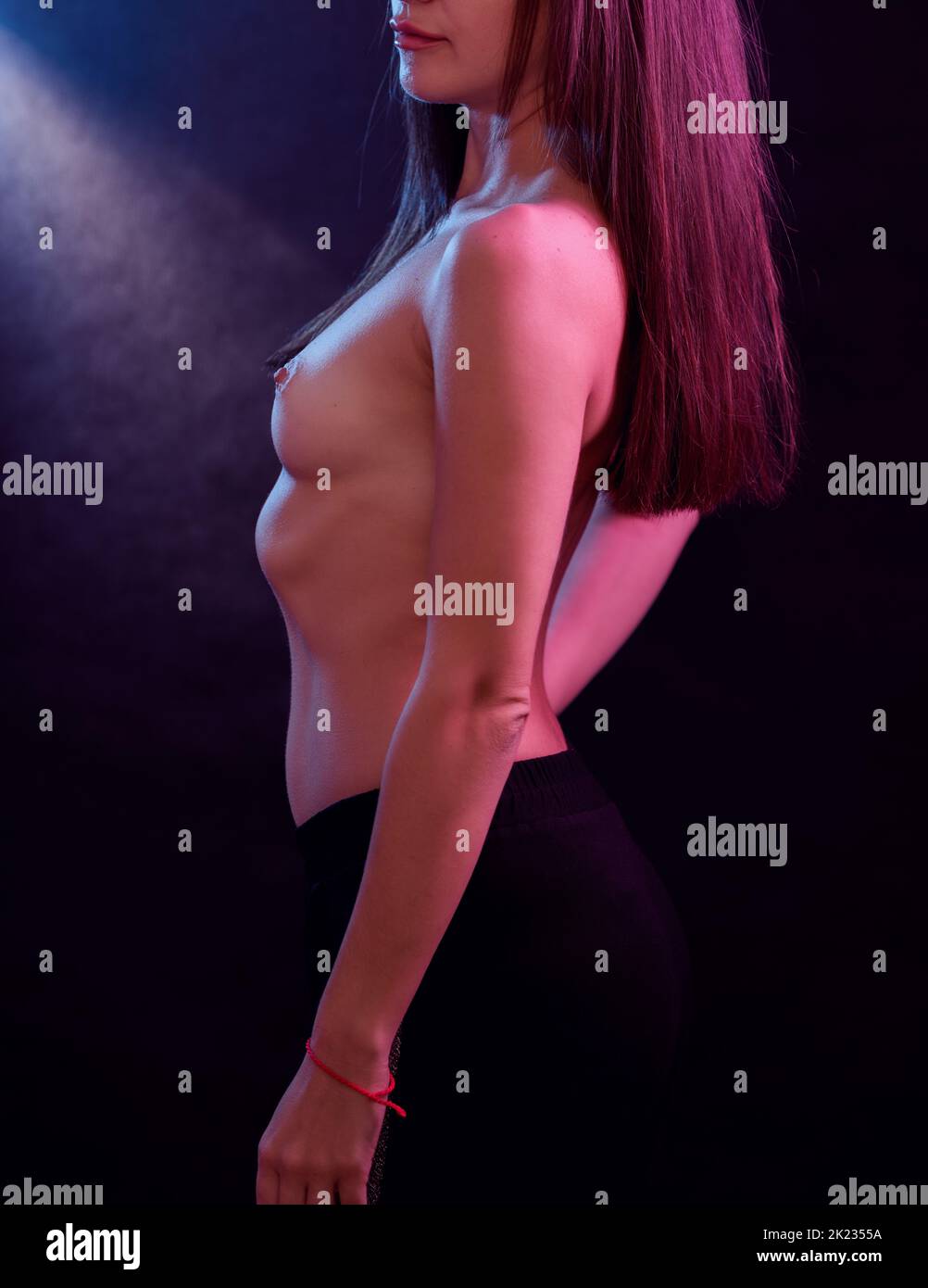 Portrait of a topless woman with colored light and dark background. Stock Photo