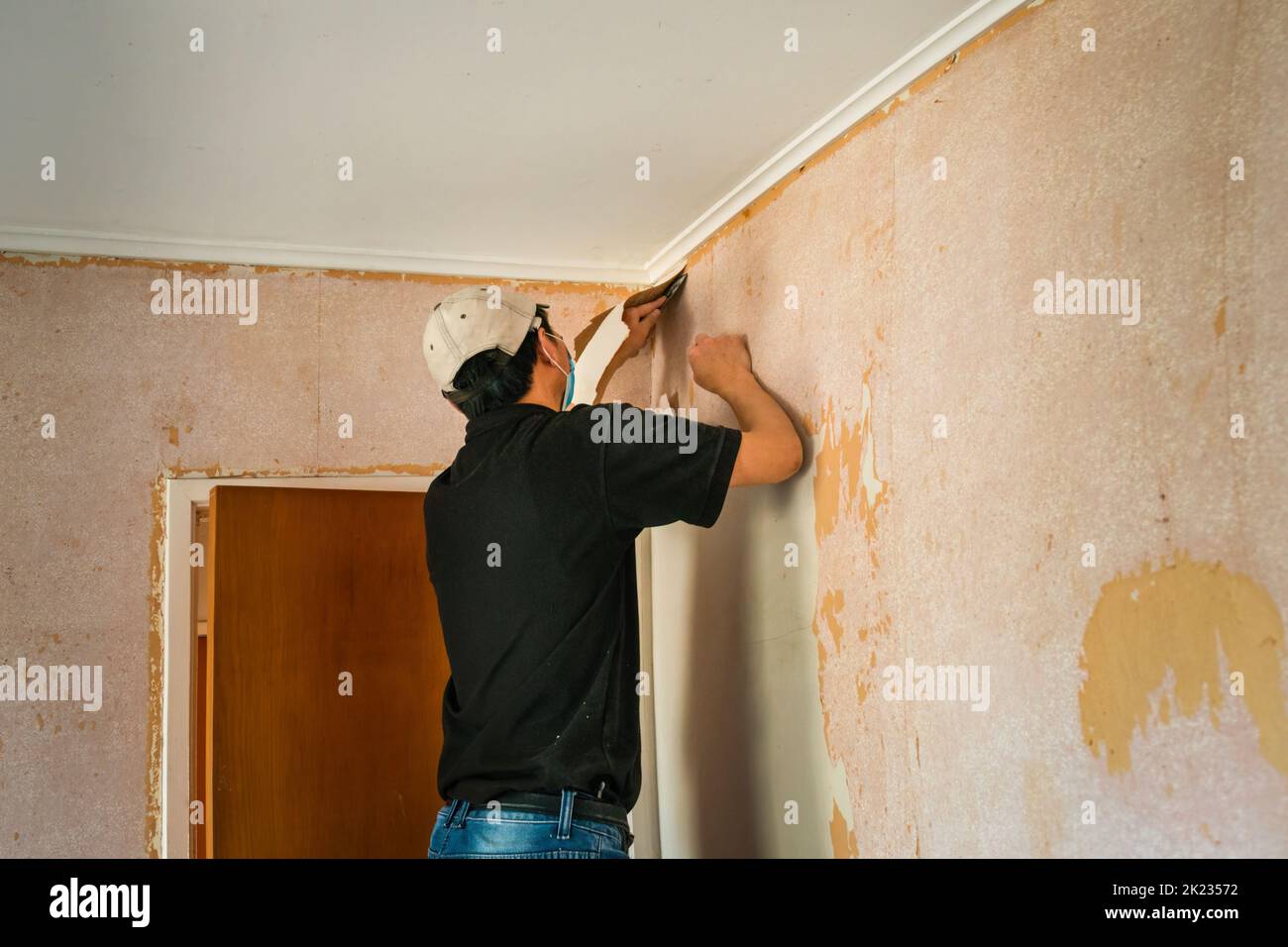 Man removing wallpaper inside an old house Stock Photo