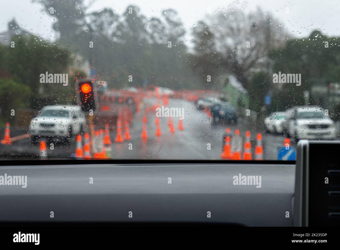 Car waiting on traffic light stopped by roadwork. Blurred traffic cones lined up road. Dunedin, New Zealand. Stock Photo