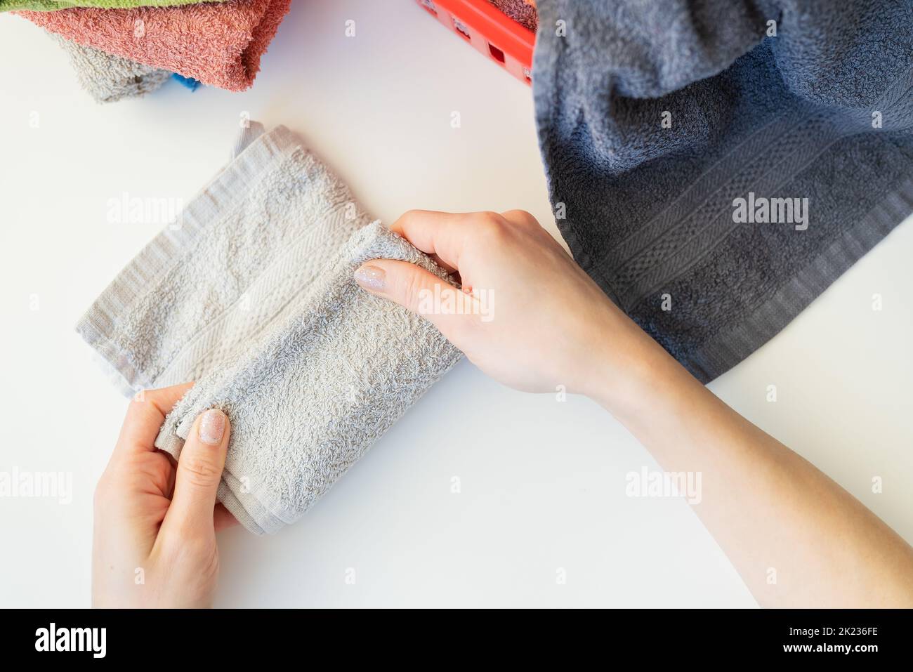 A woman's hand holds a terry towel from a clothes basket. Towel after