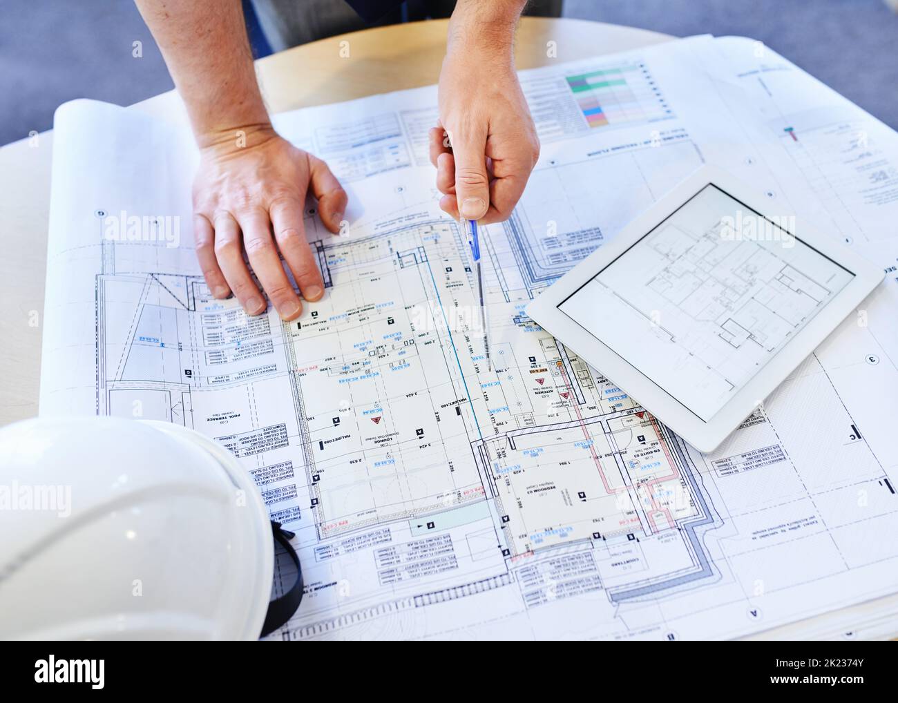 Looking for the smallest miscalculation. an architects hands examining blueprints and using a digital tablet. Stock Photo