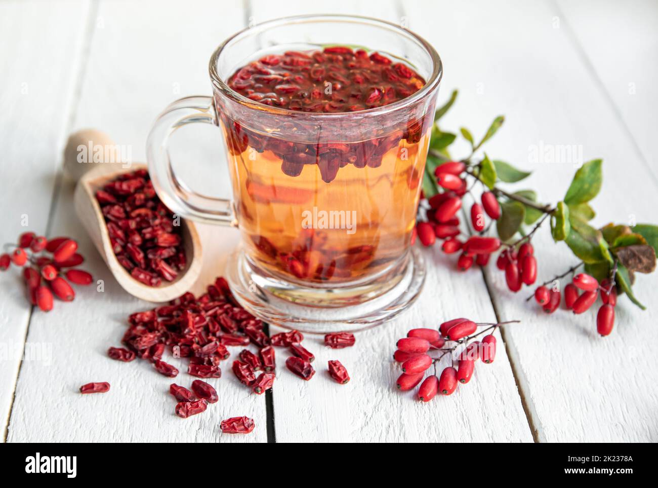 Berberis vulgaris also known as common barberry, European barberry or barberry tea drink in class mug in home kitchen. Dried and fresh berries. Stock Photo