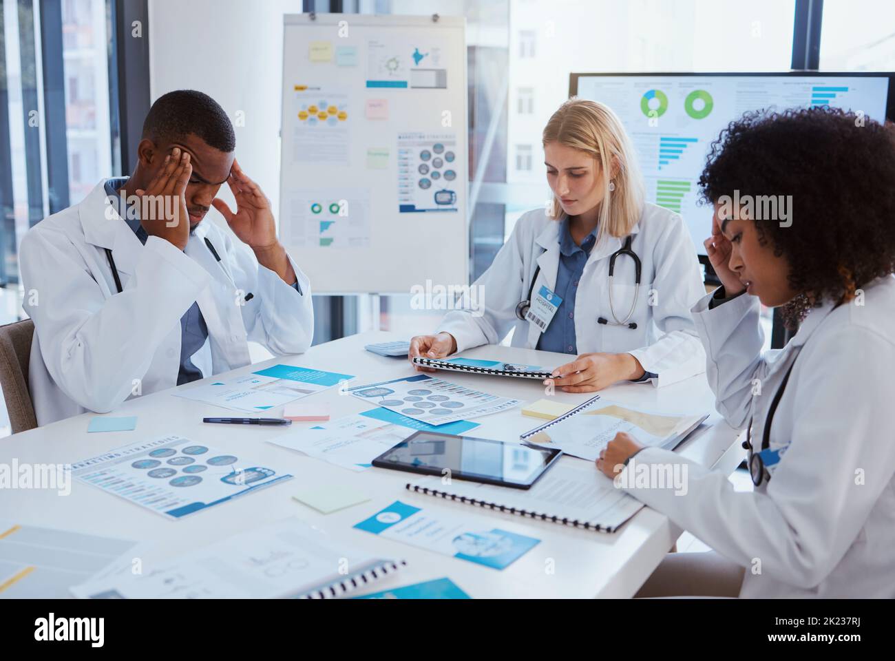 Healthcare, thinking and team of doctors in meeting with medical statistics in hospital boardroom. Data, analytics and research, overworked men and Stock Photo