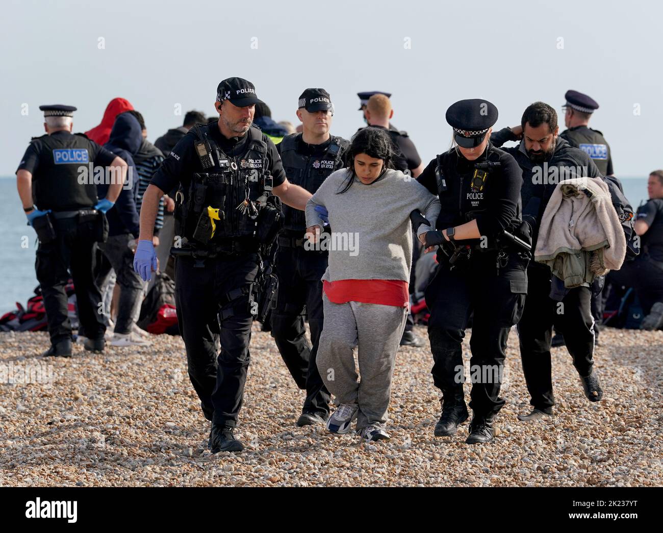 A heavily pregnant lady is helped by police officers as a group of people thought to be migrants walk up the beach in Dungeness, Kent, after being rescued in the Channel by the RNLI following following a small boat incident. Picture date: Thursday September 22, 2022. Stock Photo