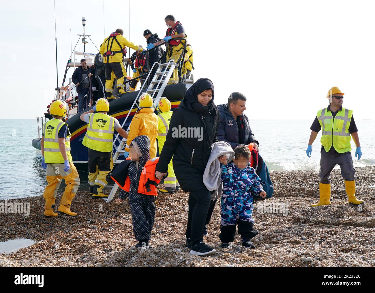 EDITORS NOTE Children's faces have been pixelated as the PA Picture Desk has been unable to gain the necessary permission to photograph a child under 16 on issues involving their welfare A young family are helped to shore as a group of people thought to be migrants arrive in Dungeness, Kent, after being rescued in the Channel by the RNLI following following a small boat incident. Picture date: Thursday September 22, 2022. Stock Photo