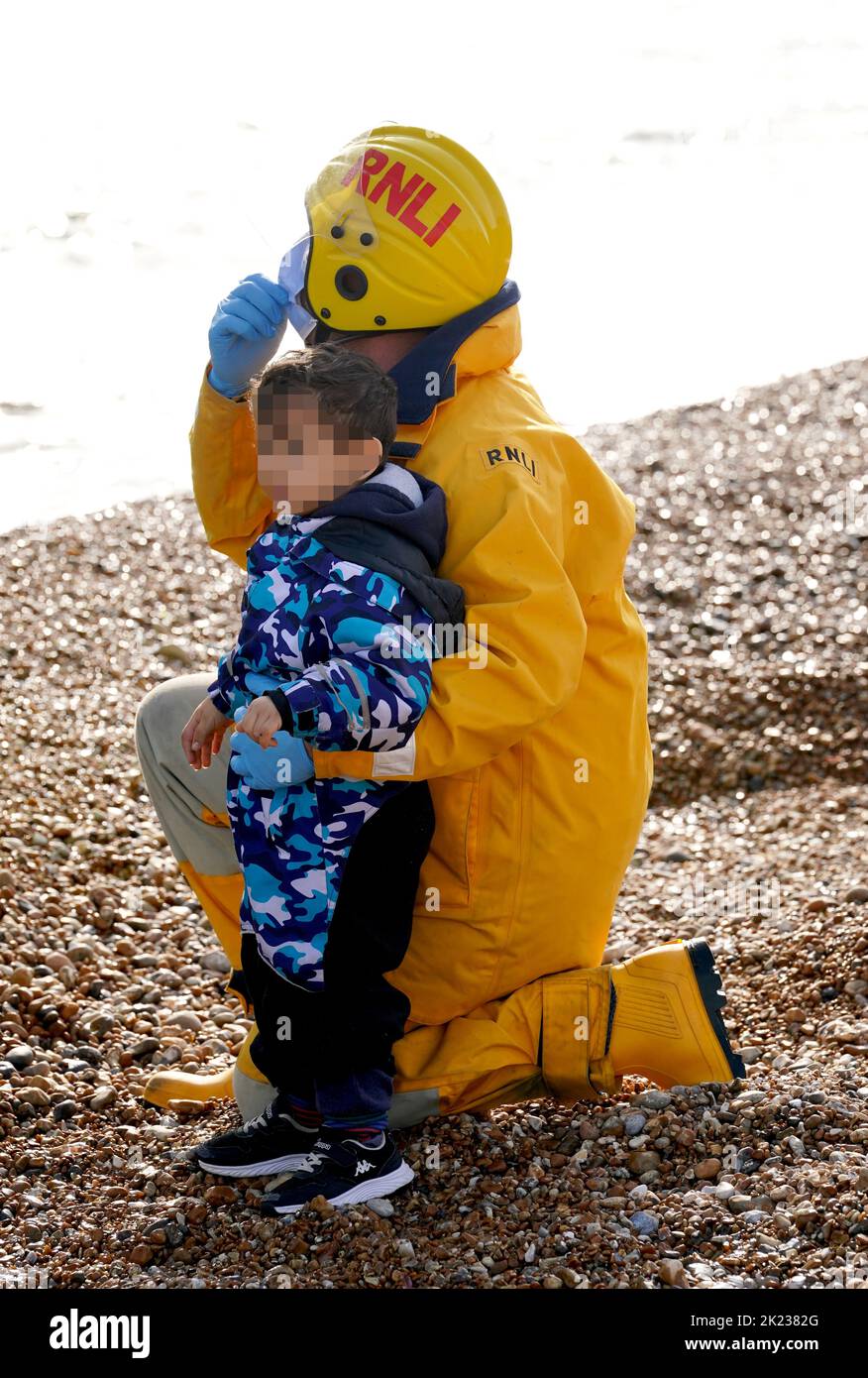 EDITORS NOTE Children's faces have been pixelated as the PA Picture Desk has been unable to gain the necessary permission to photograph a child under 16 on issues involving their welfare A young child is helped to shore as a group of people thought to be migrants arrive in Dungeness, Kent, after being rescued in the Channel by the RNLI following following a small boat incident. Picture date: Thursday September 22, 2022. Stock Photo