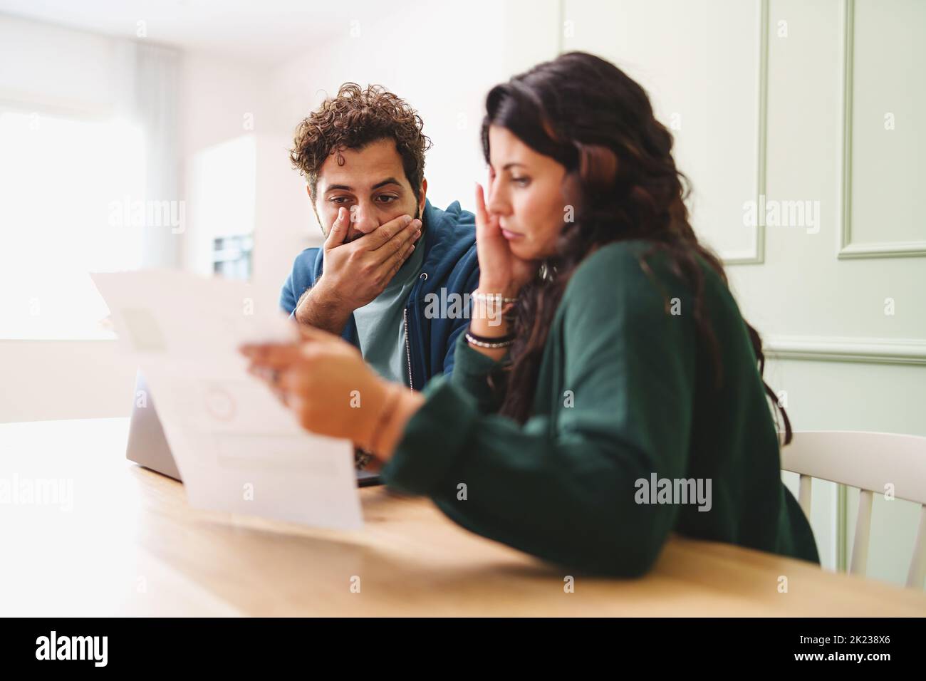 A young married couple is worried looking at the electricity bill or the arrival of very expensive taxes - lifestyle concept on the contemporary famil Stock Photo