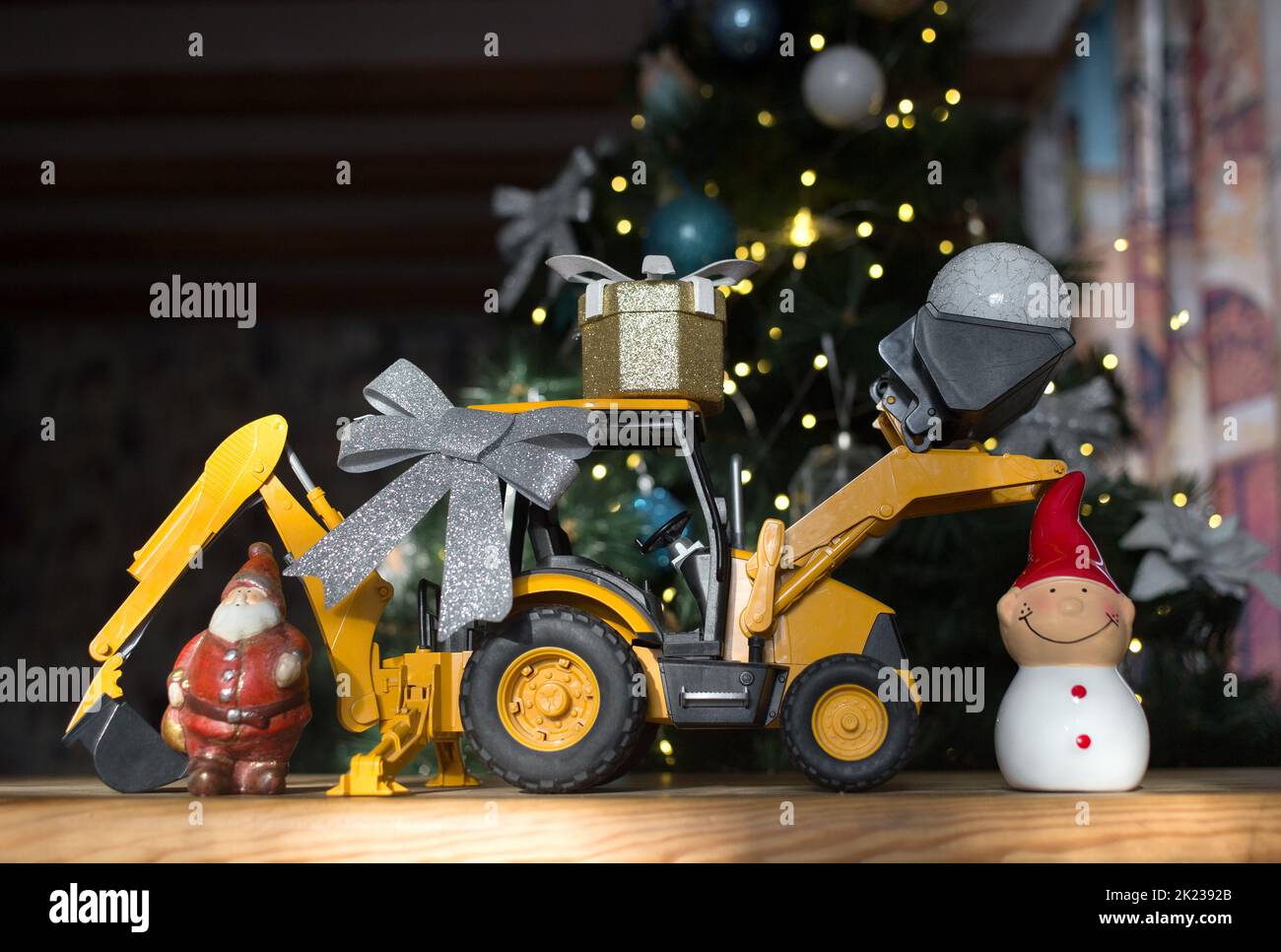 concept of christmas business greetings, new year winter holidays in construction company. toy bulldozer - excavator, gift box, figurine of Santa Clau Stock Photo