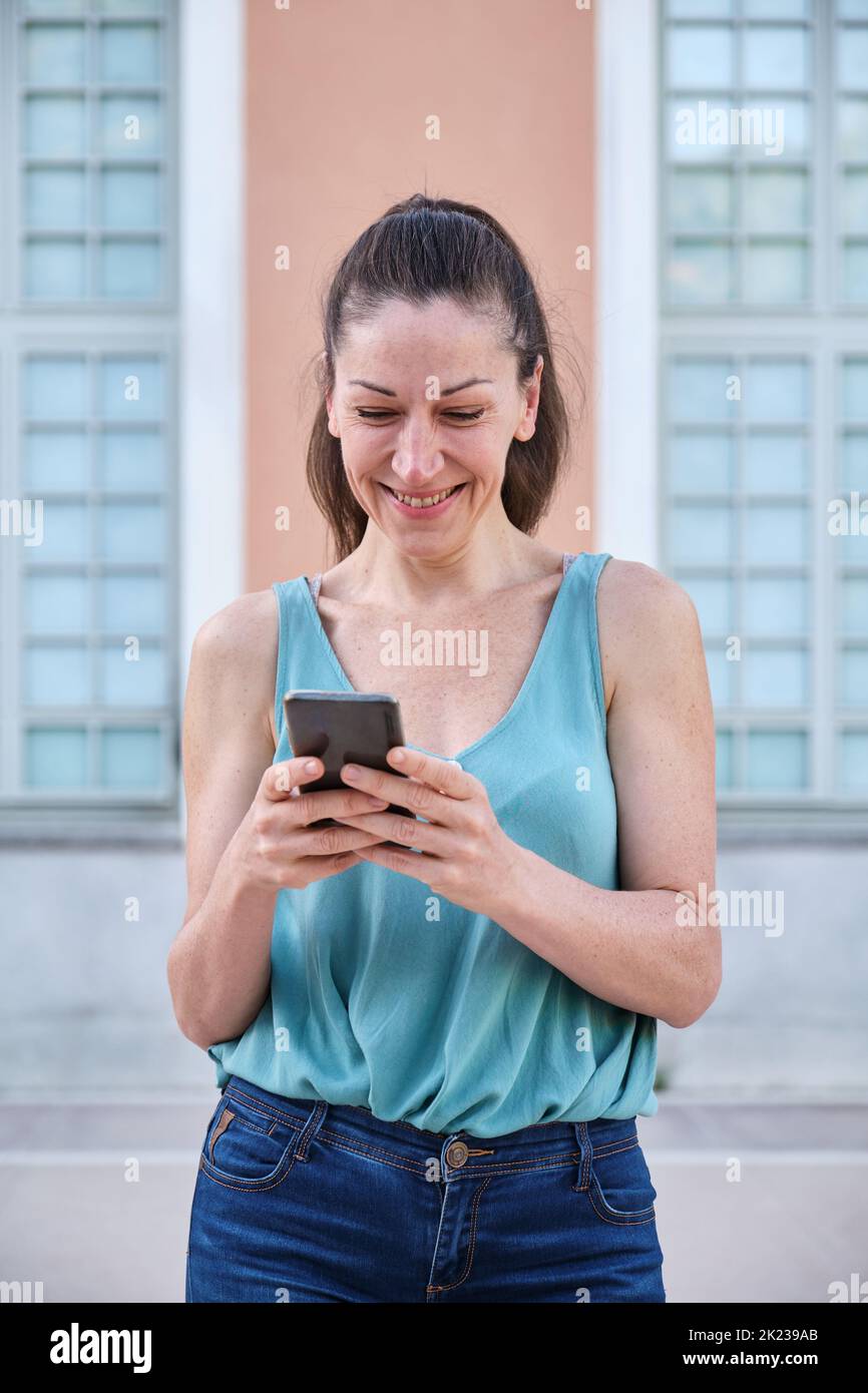 Woman chatting on the phone and smiling in the street. Stock Photo