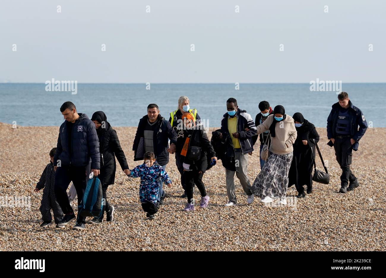 EDITORS NOTE: The PA Picture Desk has been unable to gain the necessary permission to photograph children under 16 on issues involving their welfare. This image has been provided unpixelated for customers to pixelate in their own style A group of people thought to be migrants, including young children, walk up the beach following arriving in Dungeness, Kent, after being rescued in the Channel by the RNLI during a small boat incident. Picture date: Thursday September 22, 2022. Stock Photo