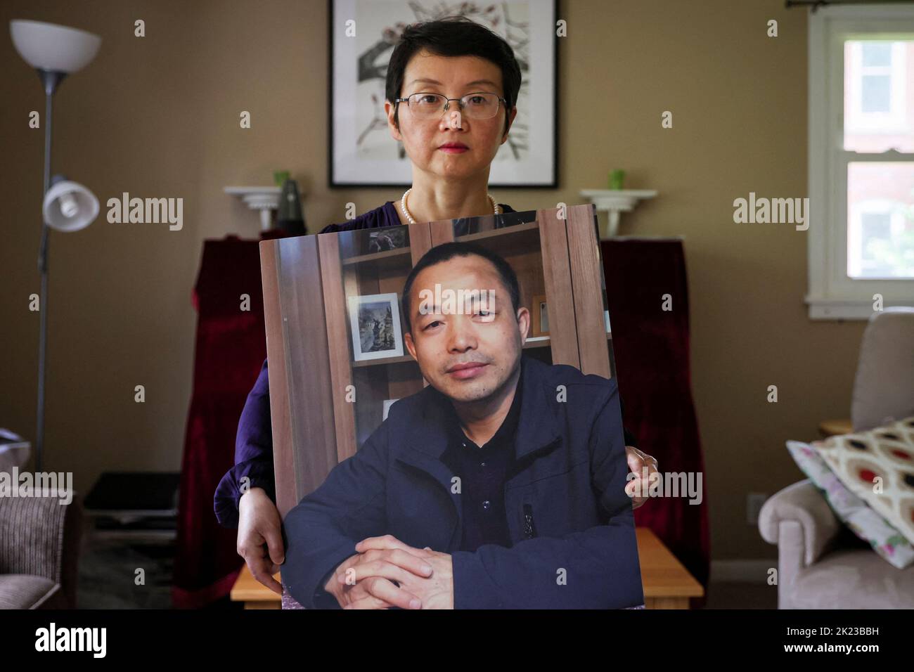 Sophie Luo Shengchun, the wife of jailed Chinese human rights lawyer, Ding Jiaxi, poses with a photo of him at her home in Alfred, New York, U.S., July 28, 2022.  To match Special Report CHINA-LAWYERS/CRACKDOWN-MAINLAND.     REUTERS/Brendan McDermid Stock Photo