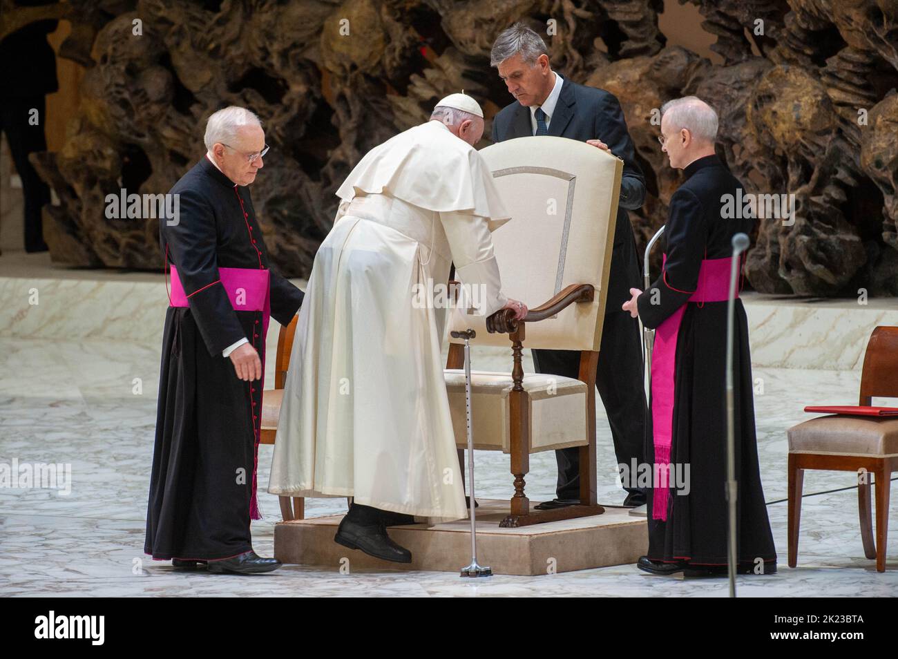 Italy, Rome, Vatican, 22/09/22. Pope Francis, flanked from left: Msgr. Leonardo Sapienza (L), his butler Sandro Mariotti (C) and Msgr. Luis Maria Rodrigo Ewart (R) rises with difficulty to sit on the chair as he arrives to leads his private audience with members of DELOITTE Global International in the Paul VI Hall. Italia, Roma, Vaticano, 22/09/22. Papa Francesco, affiancato da sinistra da: Mons. Leonardo Sapienza (L), il suo maggiordomo Sandro Mariotti (C) e Mons. Luis Maria Rodrigo Ewart (R), si alza con difficoltà per sedersi sulla sedia mentre arriva per condurre l'udienza privata con i me Stock Photo