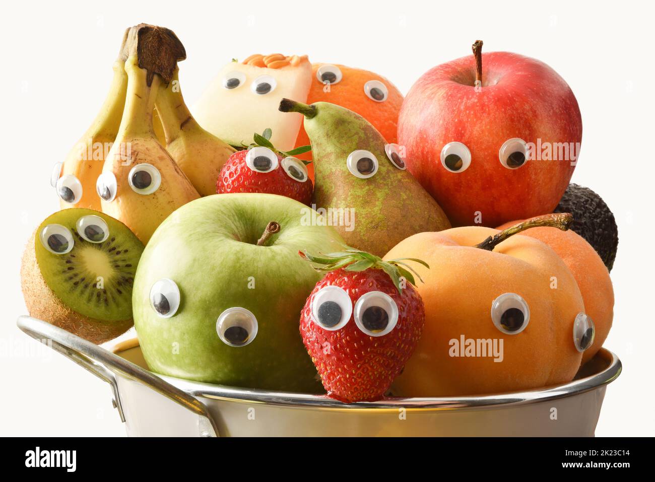 Detail of a fruit bowl full of fruit with eyes and white isolated background. Fruits and vegetables child healthy eating concept. Stock Photo