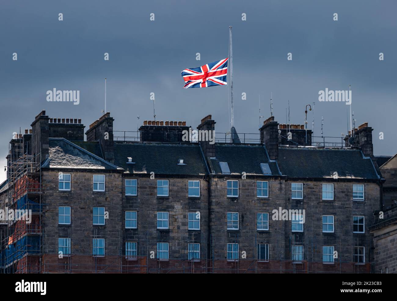 Union Jack flag flying at half mast after death of HM Queen Elizabeth II on Edinburgh city centre tenement rooftop, Scotland, UK Stock Photo