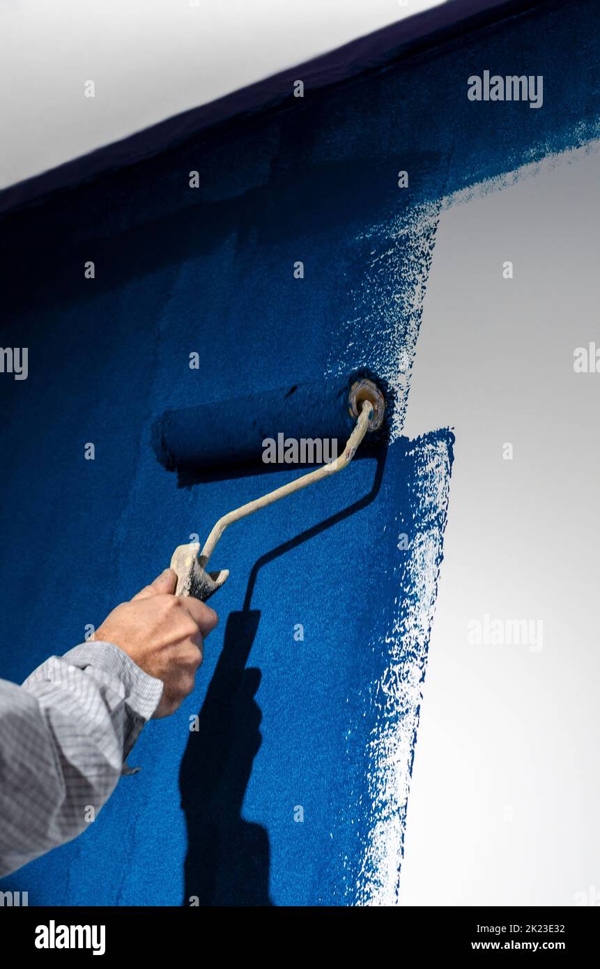 Painting a white wall in blue. Repair Stock Photo