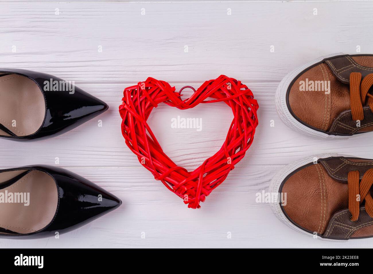 Male and female shoes and red heart. White wooden desk background. Stock Photo
