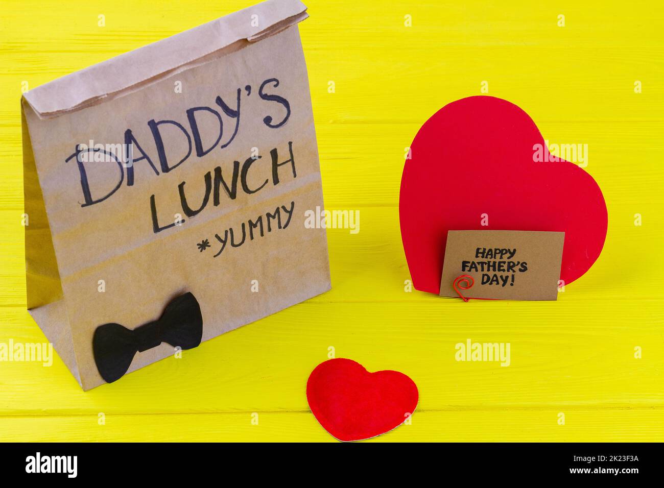 Paper bag with heart on yellow desk. Fathers day concept. Stock Photo