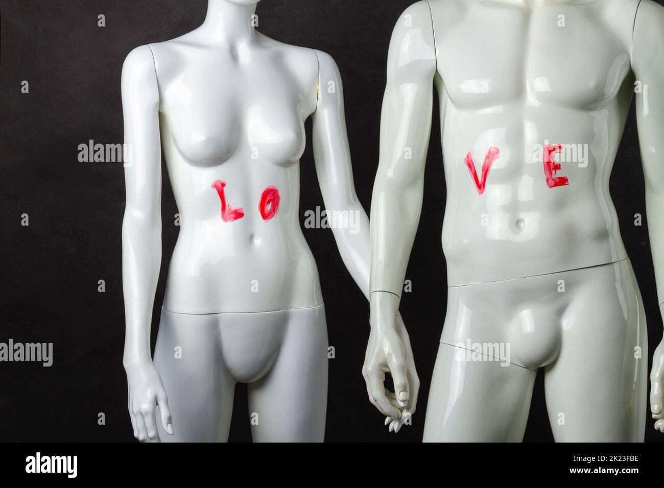 Male and female mannequins holdings hands. Love inscription on abdominal muscles. Stock Photo