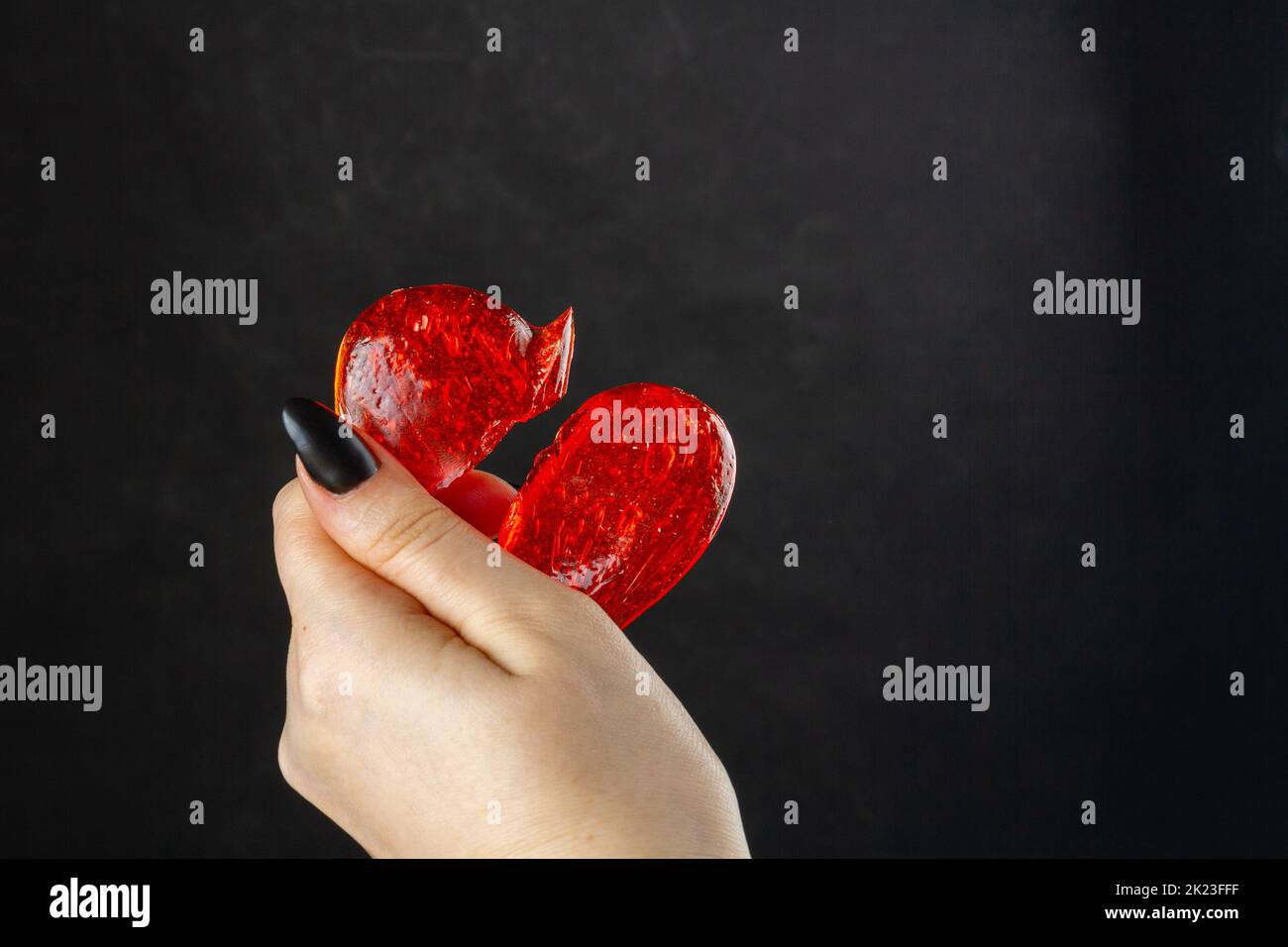 Close up of womans hand holding broken lollipop heart. Break up or divorce concept. Stock Photo