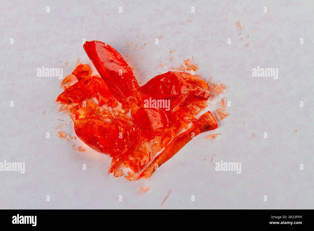 Close up broken heart lollipop on white surface. Broke up concept. Stock Photo