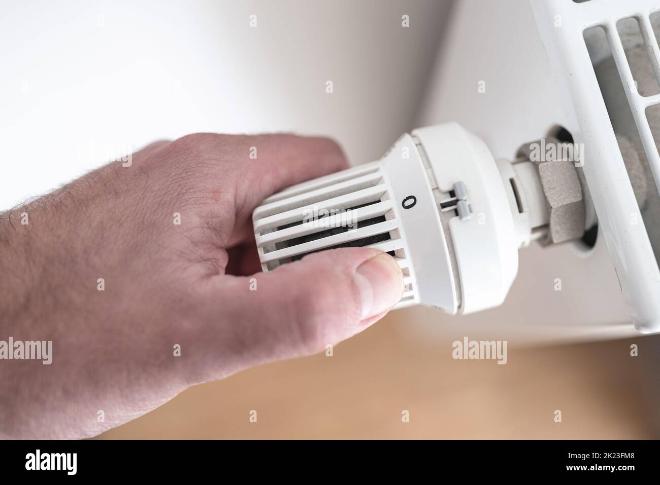close-up view of person turning down thermostat on radiator to zero to save energy and money, rising energy and heating costs concept Stock Photo