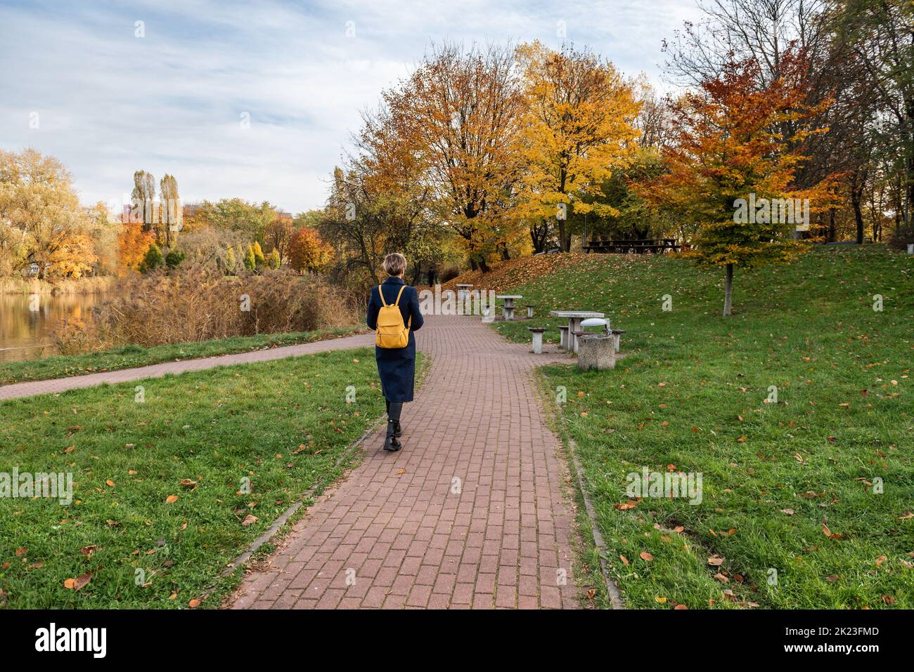 A young woman walks along a footpath in a park in the fall Stock Photo ...