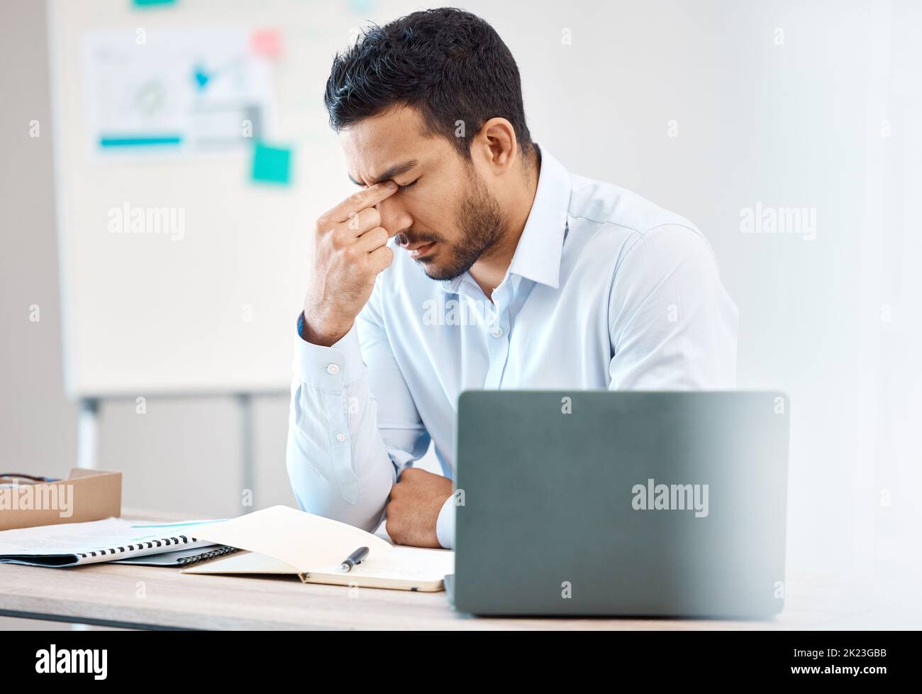 Tired, headache and eye strain from laptop with businessman while writing in notebook in corporate company. Stress, burnout and fatigue with young Stock Photo