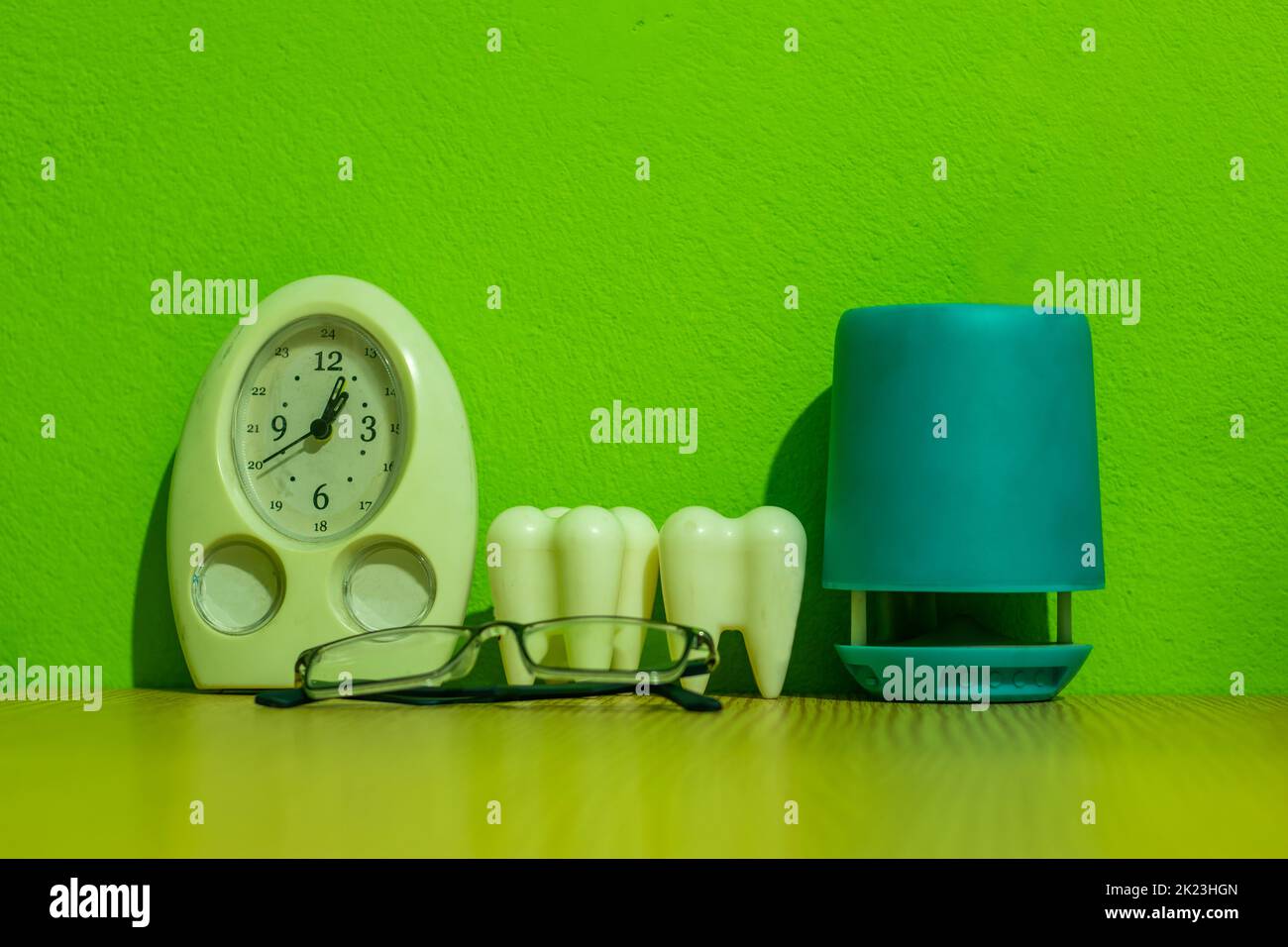 Table watch, sunglasses, pen holder, and two big teeth on a dentist's table. The dental clinic or office and dental treatment for restoring teeth. Stock Photo