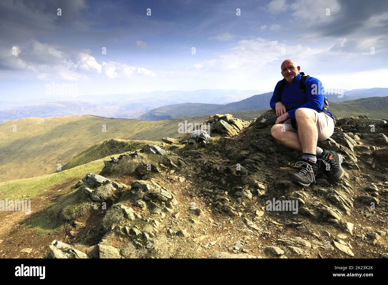 Walker at the summit of Catstye Cam fell, Lake District National Park, Cumbria, England, UK Catstye Cam fells is one of the 214 Wainwright fells. Stock Photo