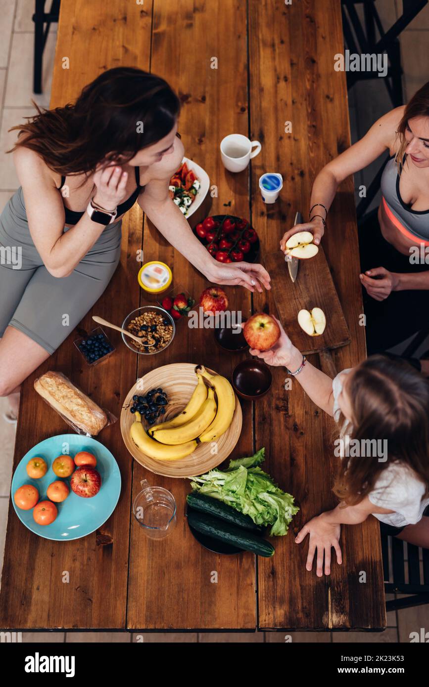 Sporty girls at the kitchen table during snack time. Stock Photo