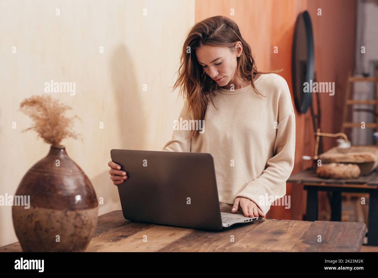 Young woman standing at desk with laptop computer. Stock Photo