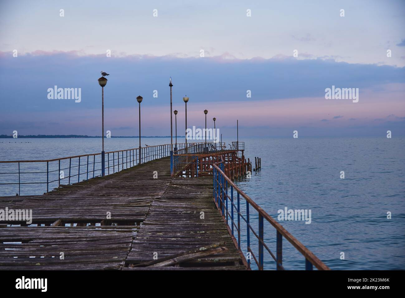 A pier stretching far out to sea against the sunset. Stock Photo