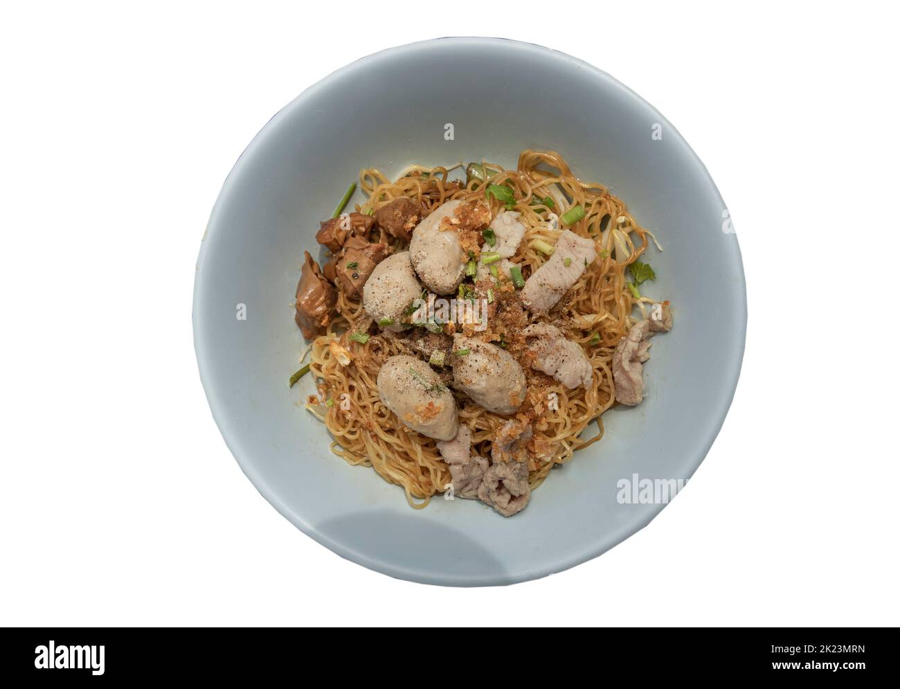 Egg Noodles with braised pork (stewed pork), fresh pork and pork balls without soup sprinkled with pepper and chopped onions in bowl isolated on white Stock Photo