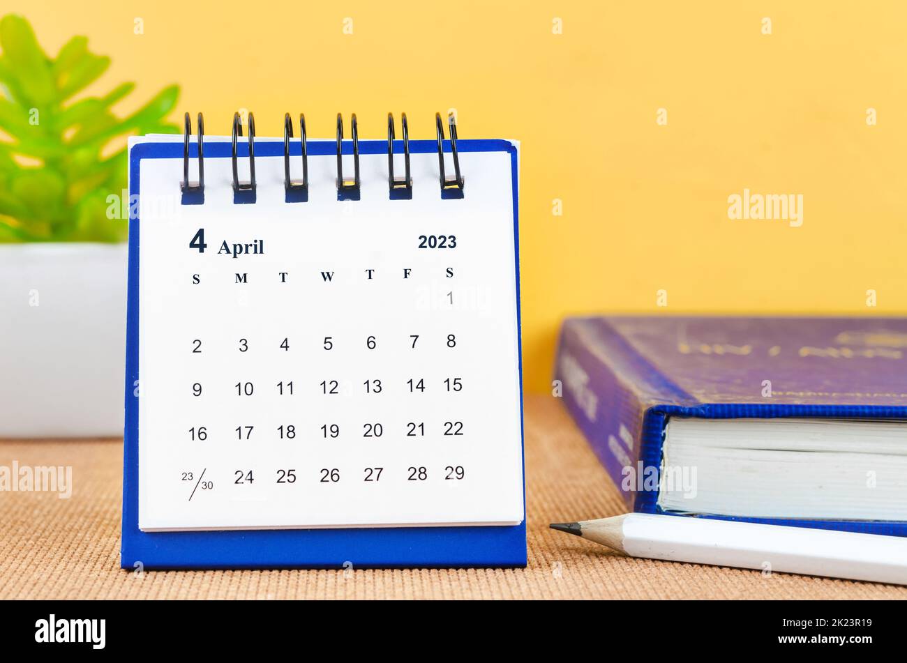 April 2023 Monthly desk calendar for 2023 with a book on yellow background. Stock Photo