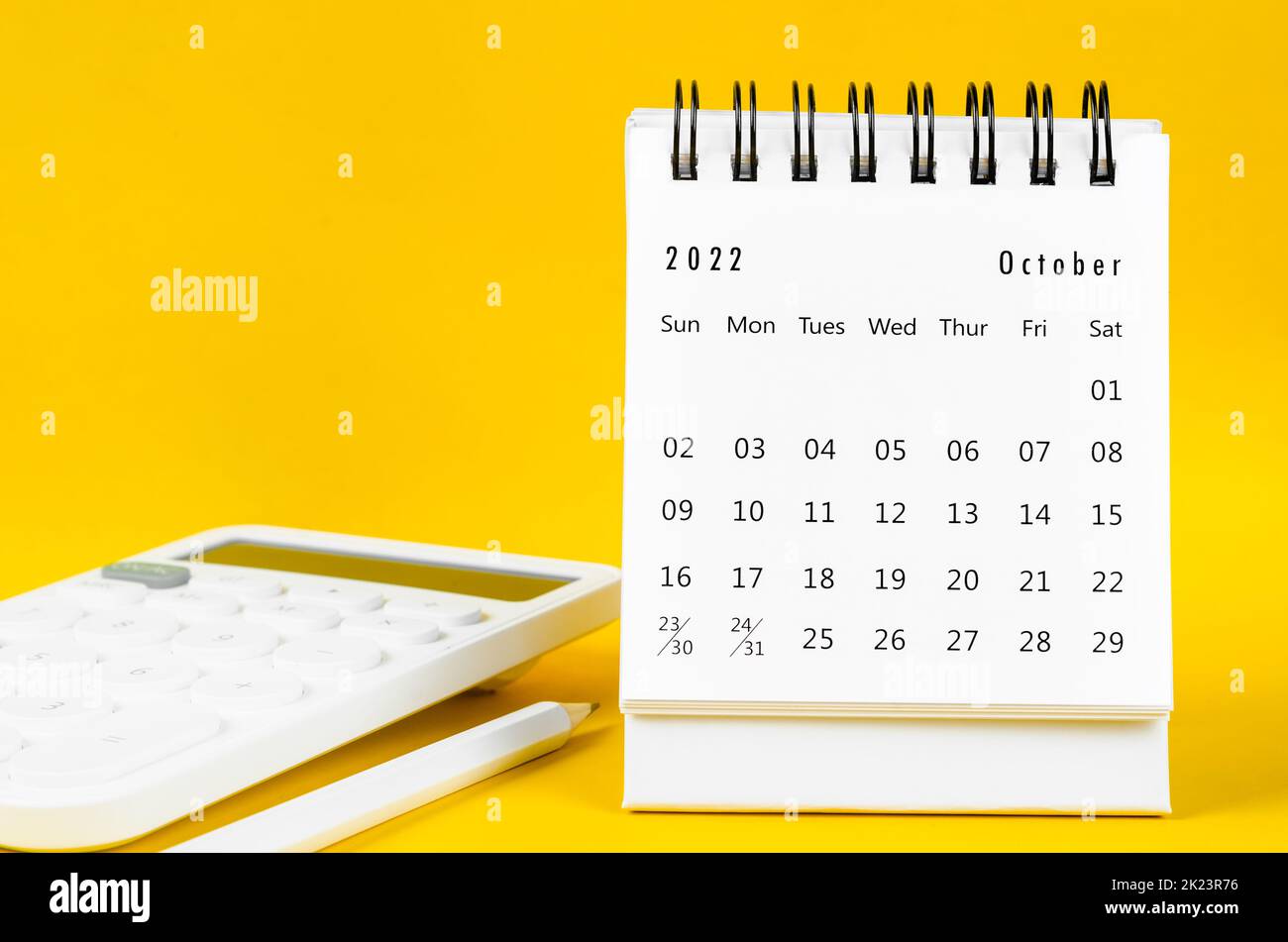 October 2022 Monthly desk calendar for 2022 year and calculator with pen on yellow background. Stock Photo