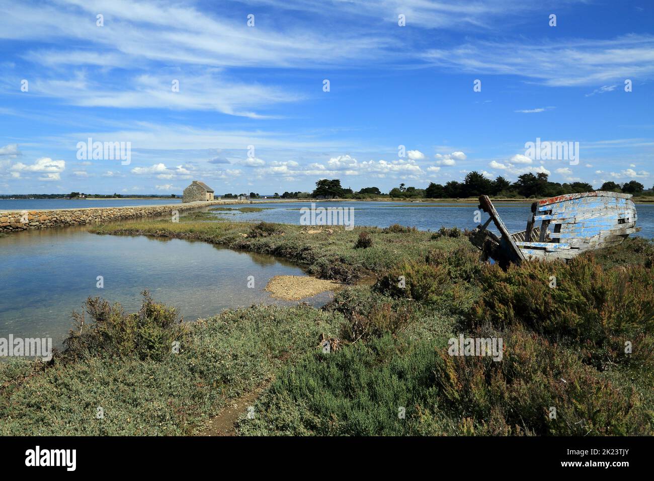 Shipwreck on the etang du moulin with sea wall and moulin a maree de Berno in the distance, Ile