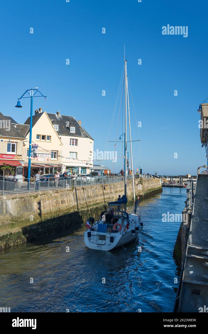 A yacht leaving the marina at Port-en-Bessin Stock Photo