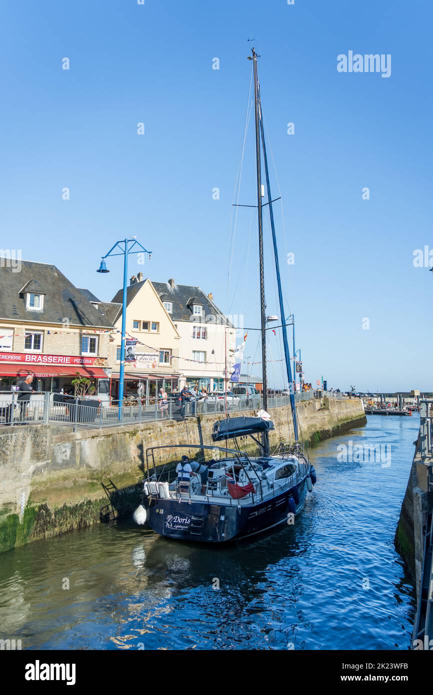 A yacht leaving the marina at Port-en-Bessin Stock Photo