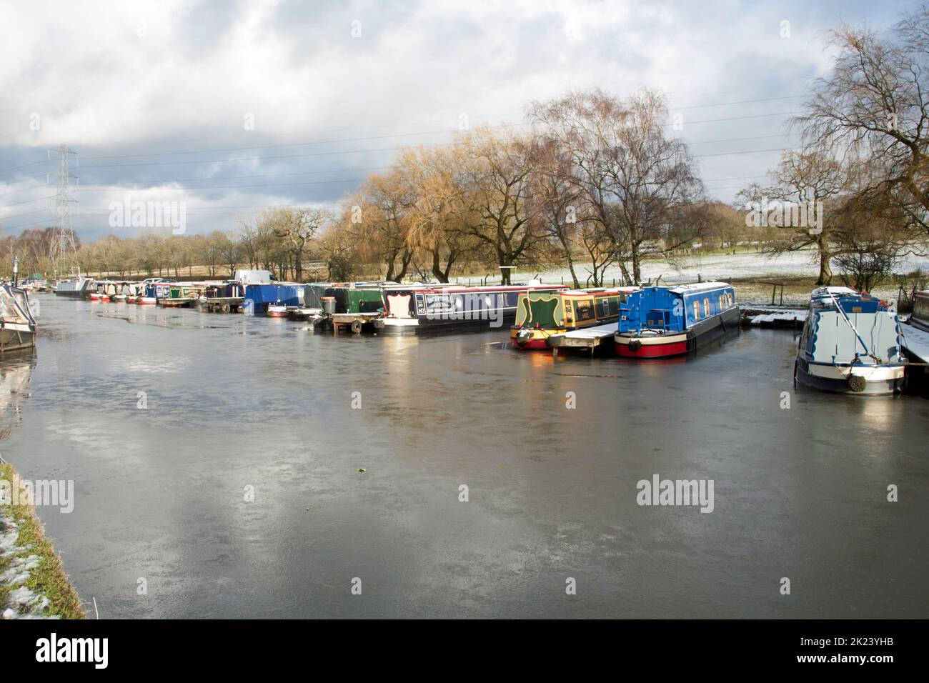 Narrow boats moored along the frozen Macclesfield Canal on a cold winter day at Higher Poynton Cheshire England Stock Photo