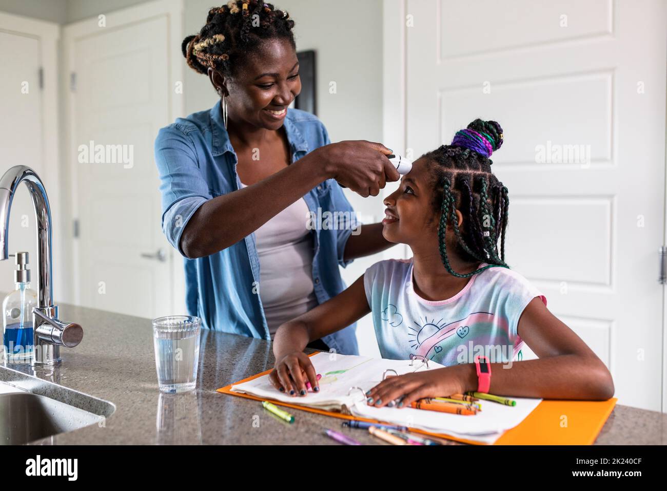 Mother taking temperature of daughter with forehead thermometer Stock