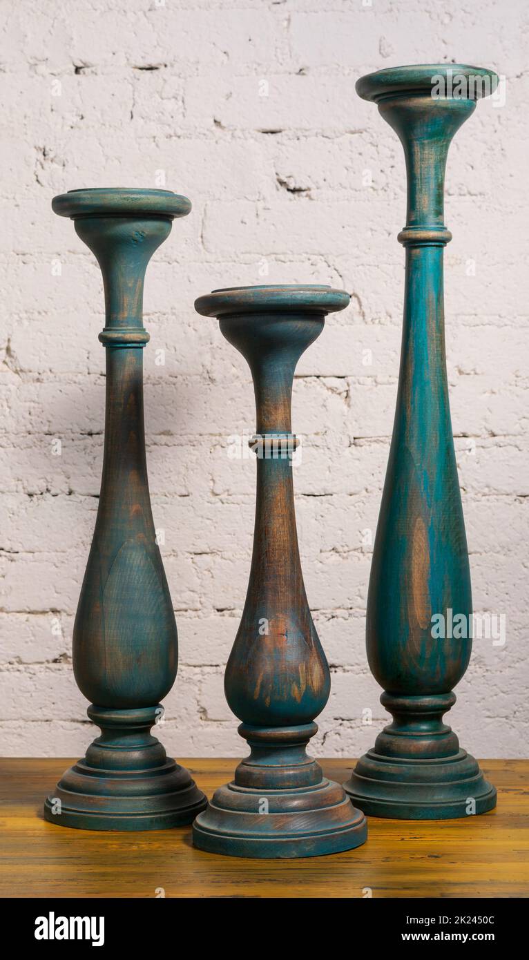 Three green vintage wooden candlesticks on a background of wooden floor