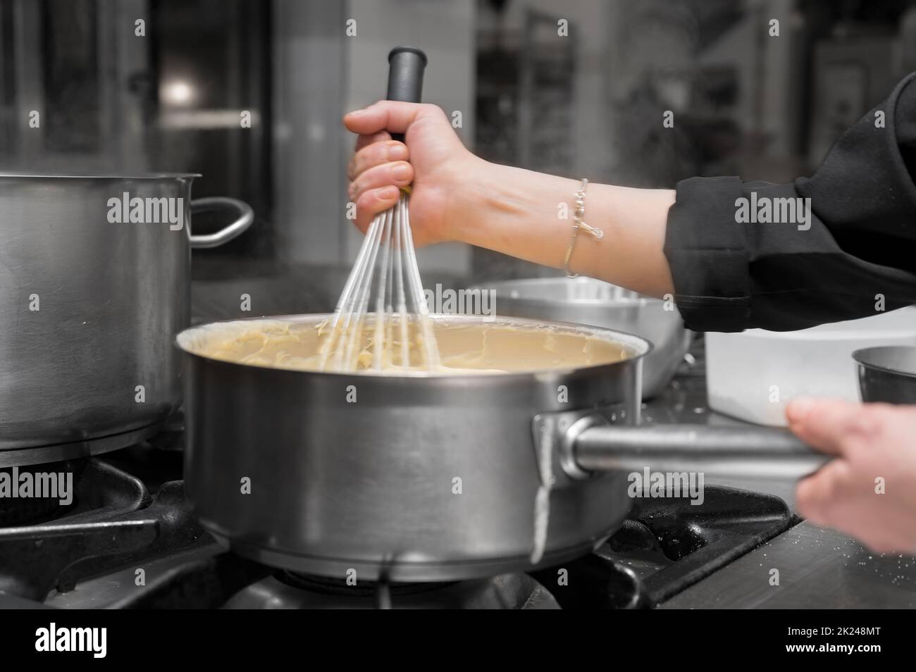 Chef stirring sauce in stainless steel pot, close-up. Professional kitchen, restaurant. High quality photo Stock Photo