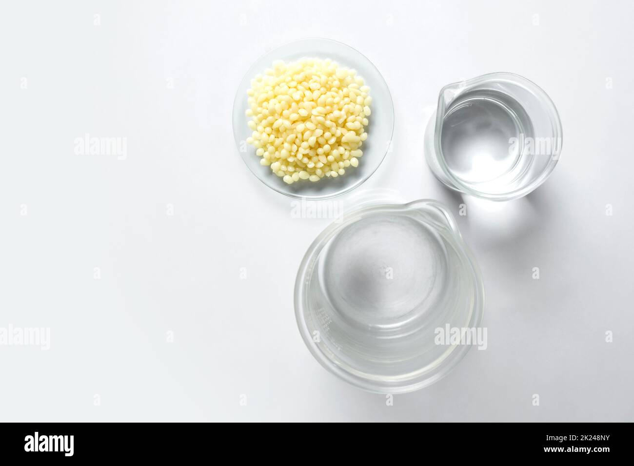 Candelilla Wax in Chemical Watch Glass and alcohol in beaker place on white laboratory table. Top view Stock Photo