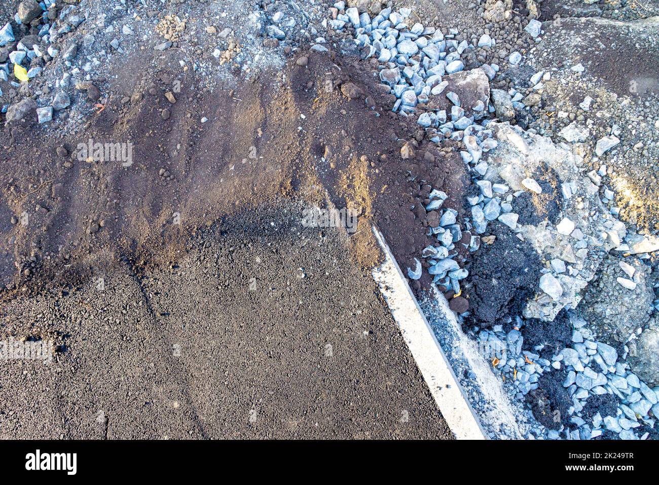 paved sidewalk suddenly breaks off against a pile of earth for a lawn, selective focus Stock Photo