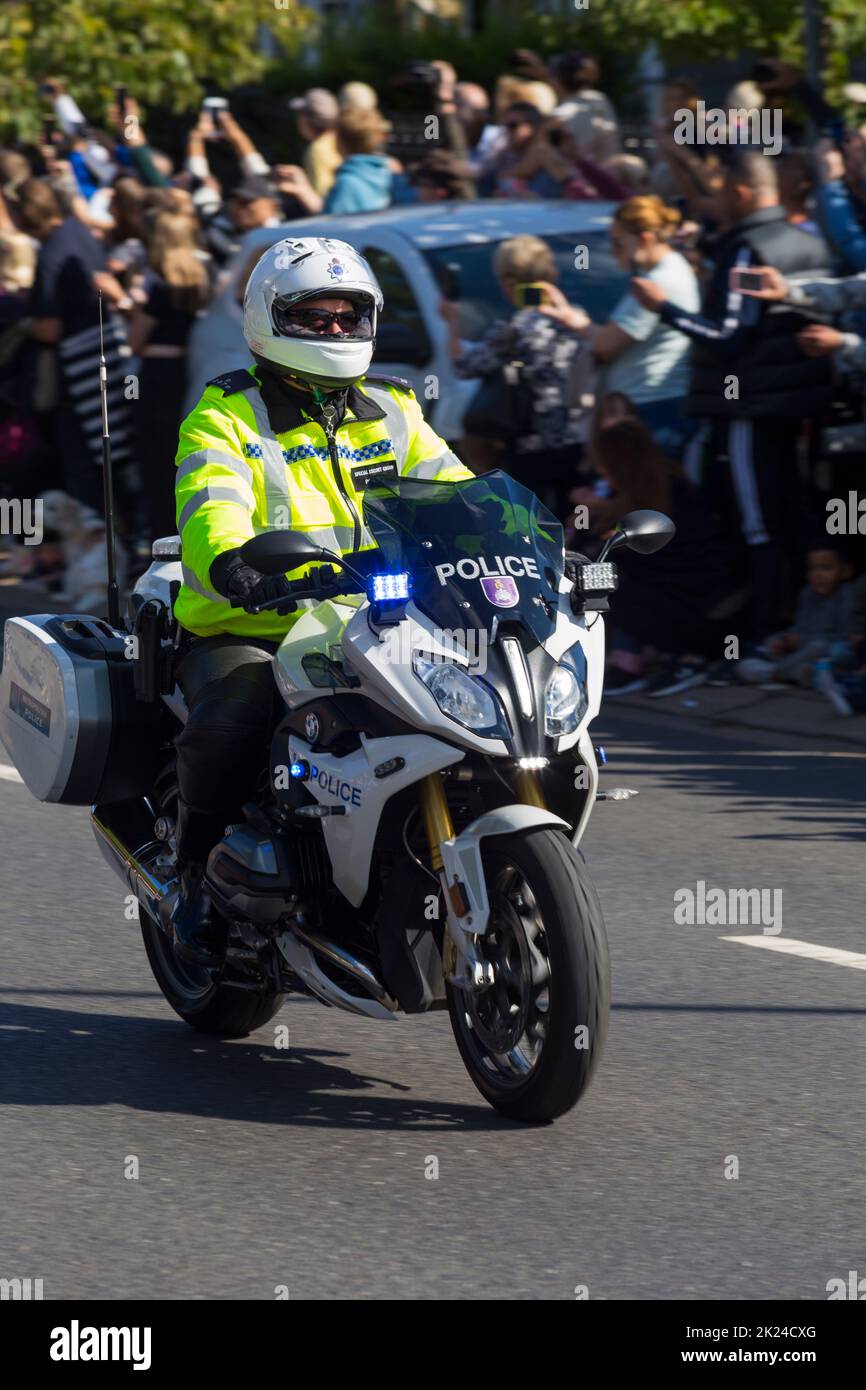 Marked police motorcycle / motor cycle / motorbike / motor bike travelling at low speed during an event. The rider / driver is part of the Special Escort Group. UK. (132) Stock Photo
