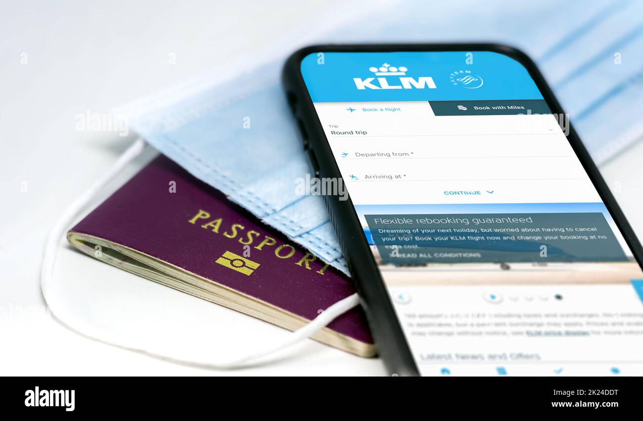 Amsterdam, NED, July 2021: phone with the KLM airlines app on the screen lying over a protective mask and a passport. Travel safety and restrictions d Stock Photo